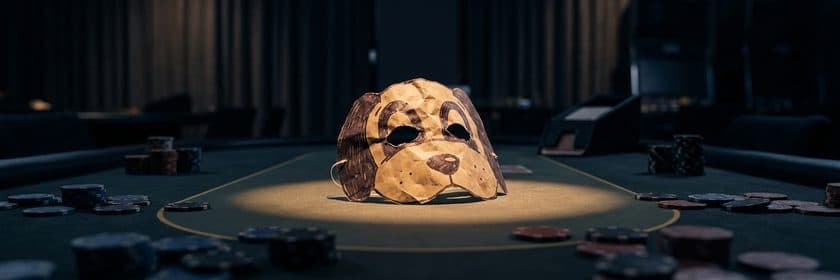 Una máscara de perro hecha de papel sobre una mesa de póker con fichas