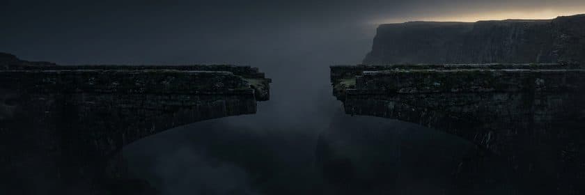 Un puente de piedra cortado al medio sobre un abismo cubierto de niebla
