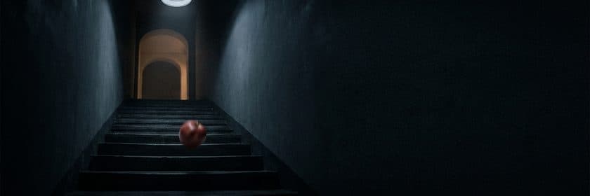 Una pelota roja bajando una escalera oscura hacia una puerta iluminada