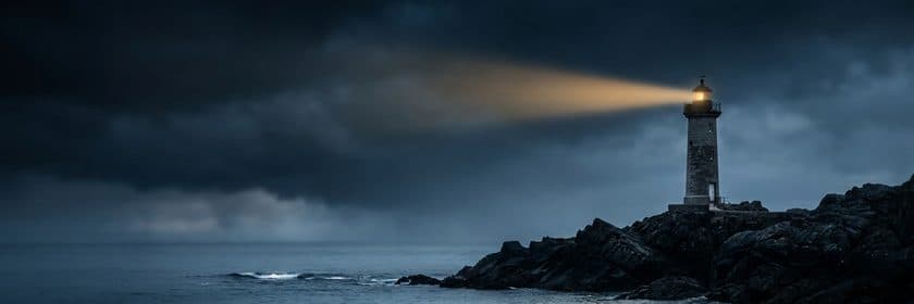 Un faro encendido sobre rocas junto al mar, bajo nubes de tormenta